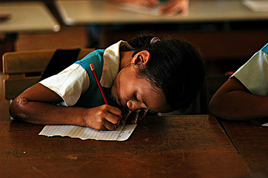 tuvalu,funafuti,schoolgirl,in,blue,uniform,writing,on,a,paper,the,classroom