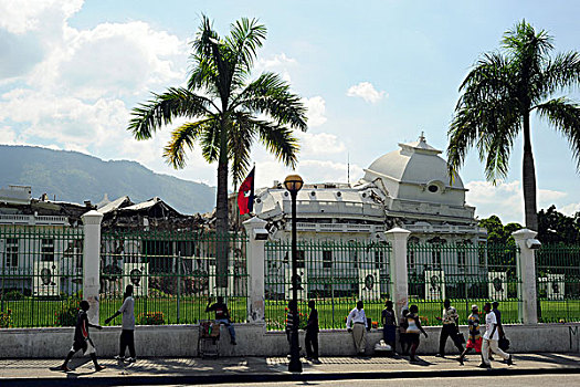 haiti,port,au,prince,champs,de,mars,camp,young,adults,walking,in,front,of,destroyed,presidential,palace