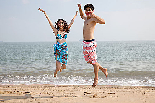 时尚青年人在沙滩上跳跃