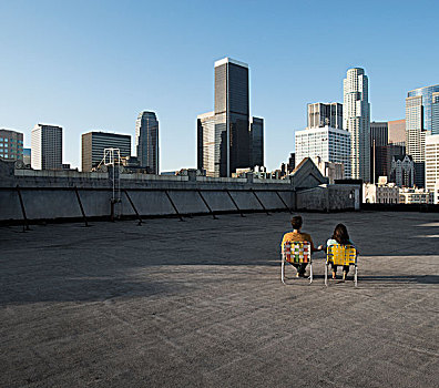 情侣,男人,女人,坐,折叠躺椅,屋顶,远眺,城市,摩天大楼
