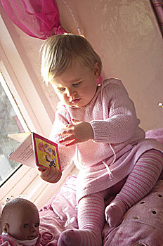 女孩,看,坐,人,孩子,幼儿,1-2岁,金发,全身,室内,在家,照料,枕头,粉色,休闲,笔记本,书本,娃娃