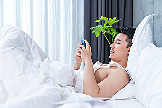 年轻男子在床上玩手机