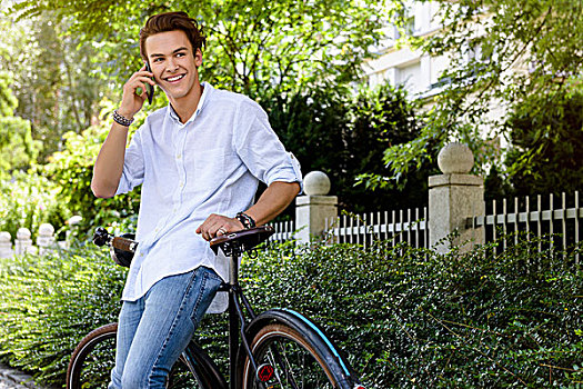 男青年,倚靠,自行车,智能手机,看别处,微笑
