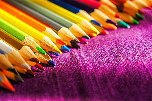 彩色铅笔摆放在紫色的麻布上