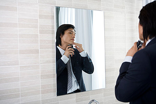 一个男人在浴室内对着镜子准备刮胡子