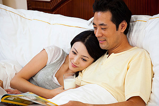 夫妻躺在床上看雜志