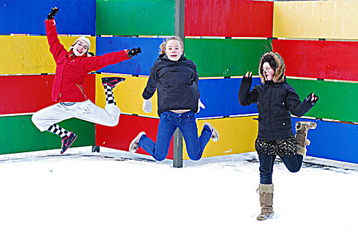iceland,reykjavik,girls,jumping,in,the,snow,with,school,building,on,background