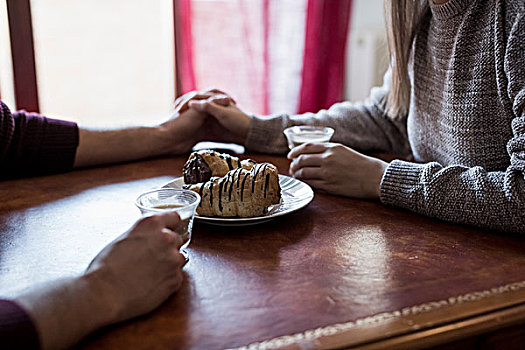 坐,夫妇,桌子,握手,拿着,咖啡杯,糕点,桌上,特写