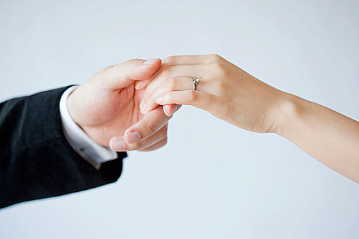 戴着结婚戒指牵手的情侣