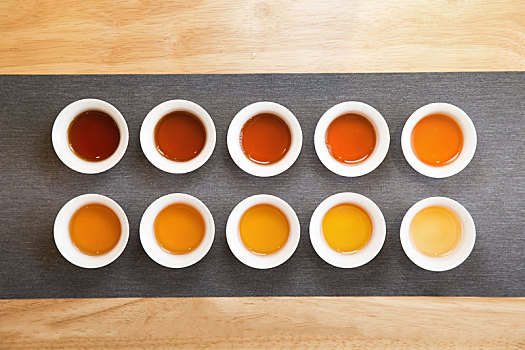 俯拍品茶茶桌上整齐排列的茶杯中茶汤颜色由深到浅渐变