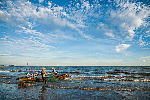 广西东兴京族万尾岛金滩渔民在海涛中拖网捕鱼