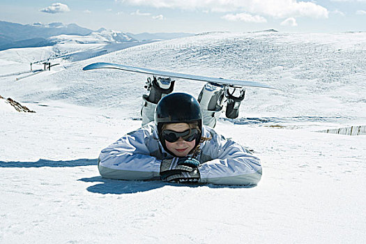 年轻,滑雪板玩家,躺着,地面,托头,手臂,看镜头,微笑