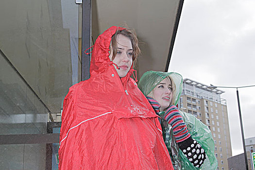 两个女人,雨衣,公交车站