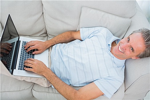 男人,躺着,沙发,打字,笔记本电脑,看镜头,微笑