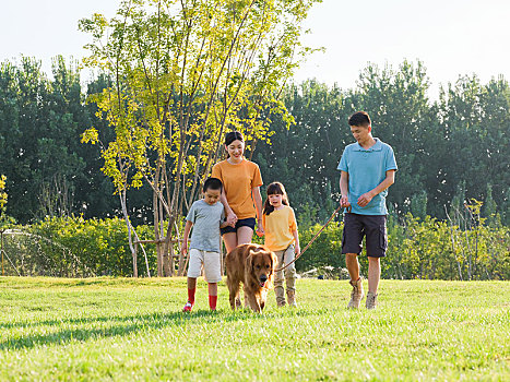 快乐的四口之家和宠物狗在公园散步