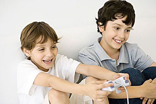两个男孩,玩,电子游戏,一起,一个,拿着,手柄,微笑