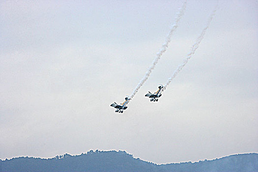 首届重庆大足航展上,英国御风飞行队的双翼飞机在进行两机相交空中芭蕾特技飞行表演