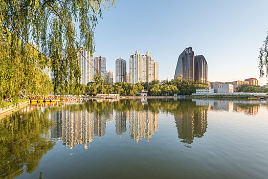 黄昏中国北京朝阳公园湖边的树林建筑