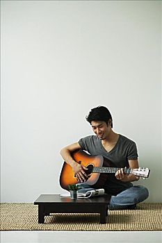 男青年,坐在地板上,弹吉他