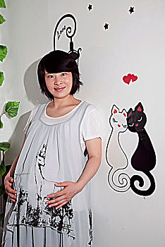 站在绘有猫咪图案的背景墙前的孕妇