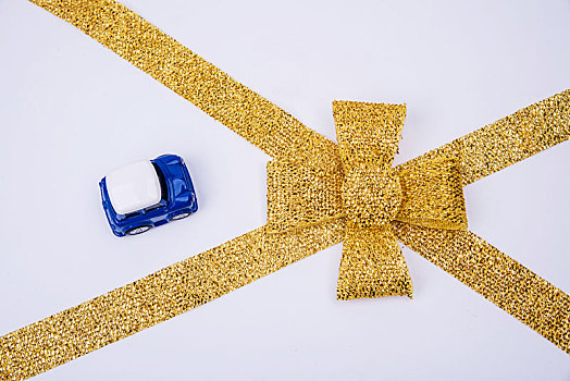 白色背景中的金色蝴蝶结和模型小汽车
