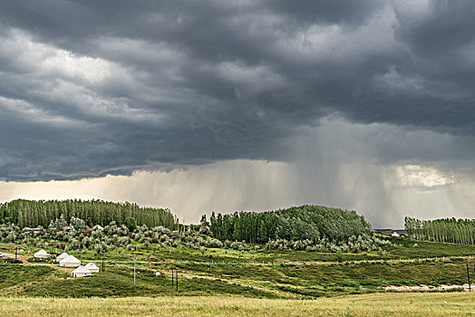 阴天积雨云下的山坡草原村庄