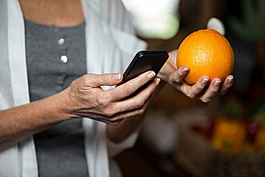 腰部,女性,拿着,橙色,打手机,超市