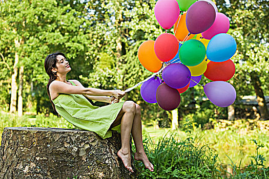 女青年,拿着,束,气球,坐在树上,树桩