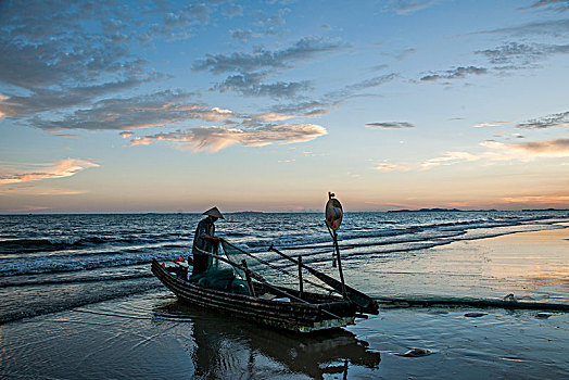 广西东兴京族万尾岛金滩渔民在晚霞中出海捕鱼
