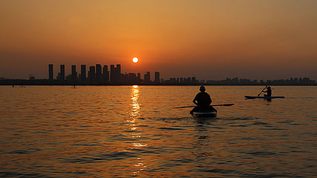 黄昏夕阳下湖面上的划船人剪影
