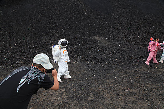 内蒙古火山口游客穿宇航服拿国旗拍照,宛若登陆外星球