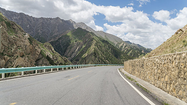 中国新疆夏季蓝天白云下高山草原g217独库公路弯道特写