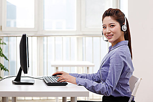 商务女士头戴耳机使用台式电脑