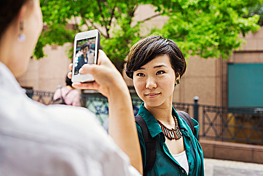 两个女人,黑发,穿,白色,绿色,衬衫,站立,户外,照相,手机,微笑