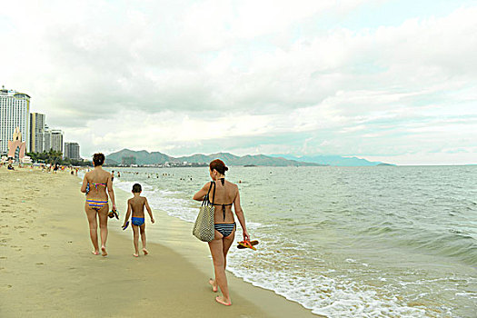 越南芽庄,一家人赤脚漫步在海边沙滩上