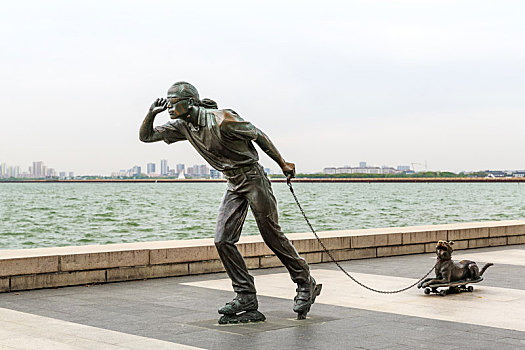 中国江苏省苏州金鸡湖湖畔公园滑板遛狗雕塑