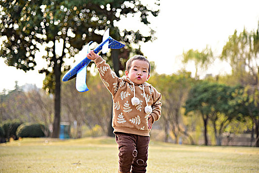 秋天草坪上玩飞机的小朋友