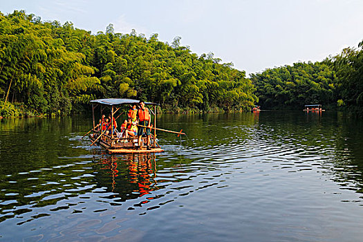 很多穿着救生衣的游客划竹筏游览湖光山色