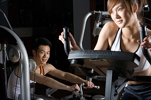 一位先生和一位女士在用器械健身