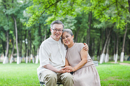 幸福的老年夫婦坐在戶外公園的椅子上