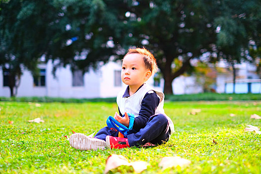 小男孩坐在电子科技大学沙河校区的草坪上