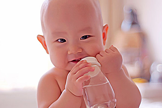 笑对镜头抱着奶瓶的婴儿特写