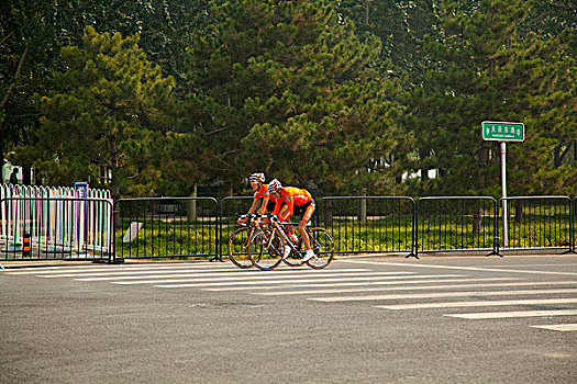 两名自行车穿橘色运动服的运动员骑着自行车在熟悉赛道