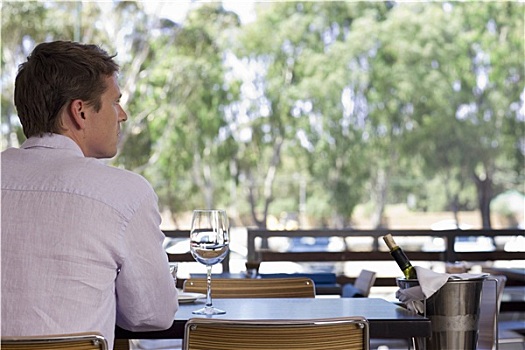 男人,坐,桌子,餐馆,露台,葡萄酒杯,冰桶,后视图