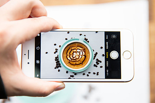 手持iphone手机摄影一杯卡布奇诺咖啡