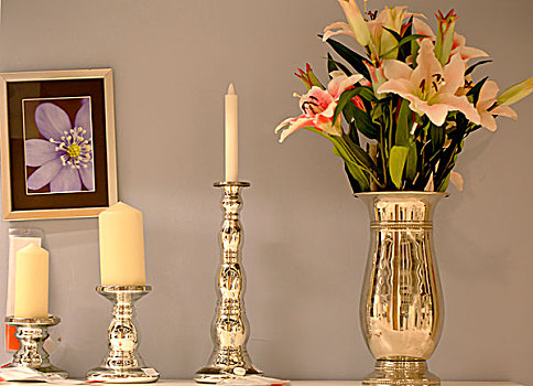三个蜡烛台插着白色的蜡烛和一盆花并排放置