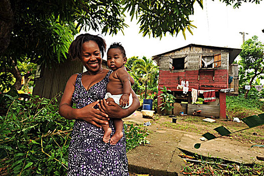 dominica,carib,territory,mother,holding,fat,baby,in,front,of,house