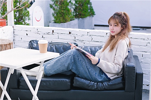 温暖的冬天女生坐在沙发上看书喝咖啡