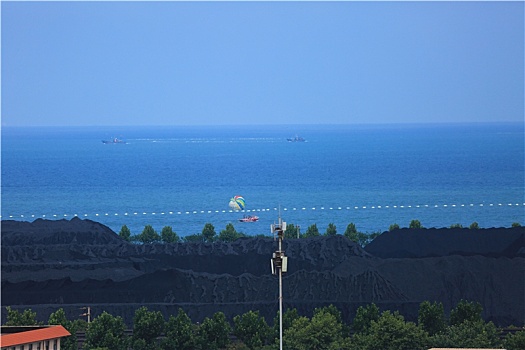 山东省日照市,蓝天碧海映衬下的港口煤炭堆场整洁有序