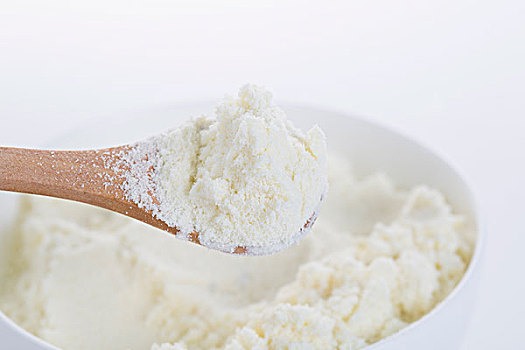 奶粉在白色的碗中,以及一个小木勺